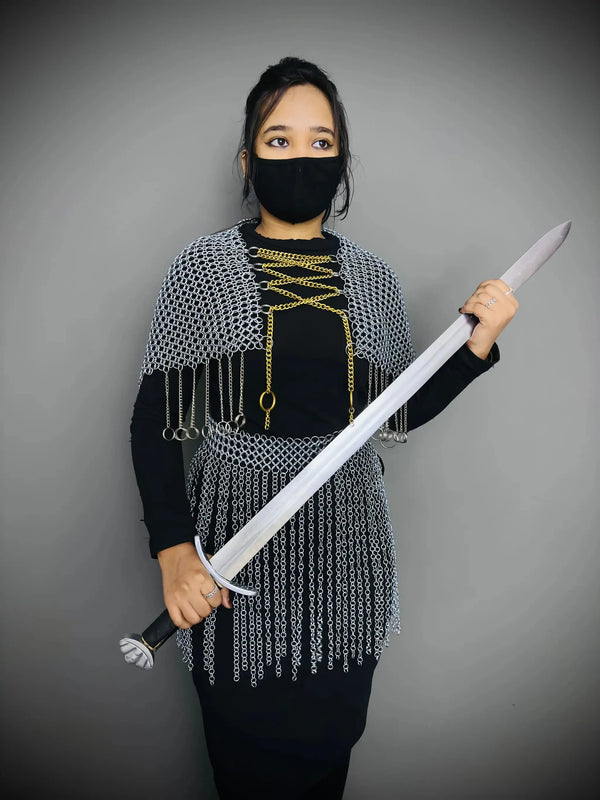 Person wearing chainmail and holding a sword against a gray background