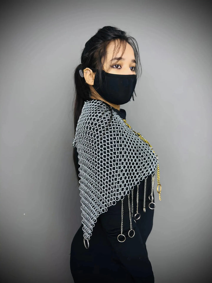 Person wearing a chainmail shawl with tassels on a gray background