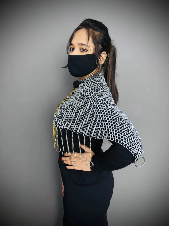 Person wearing a chainmail shirt over a black dress with a plain background