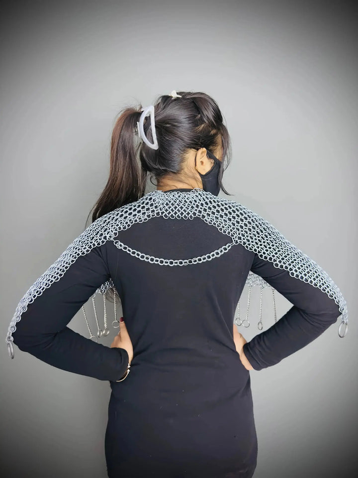 Person wearing a black outfit with white lace sleeves against a gray background