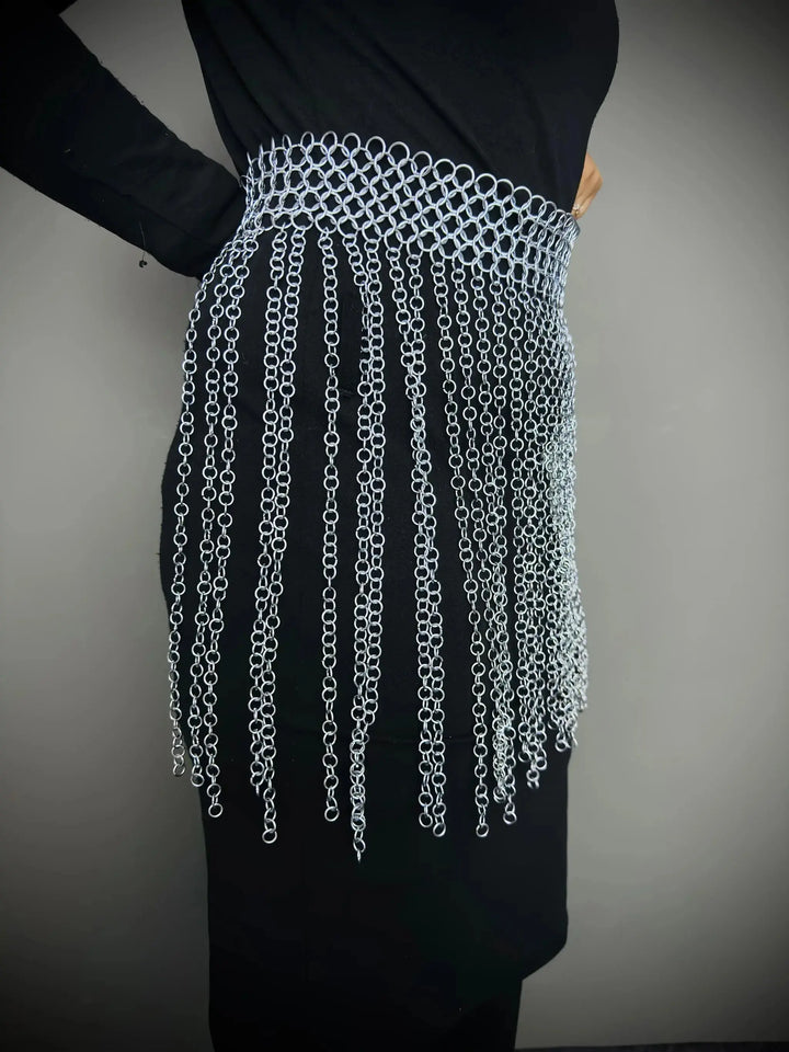 Person wearing a chainmail skirt against a plain background