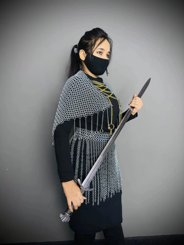 Person wearing chainmail and holding a sword against a gray background