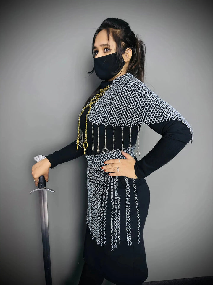 Person wearing chainmail with a sword against a gray background
