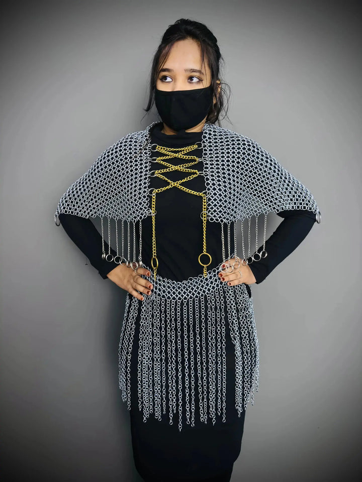 Person wearing a chainmail poncho with fringe details on a gray background