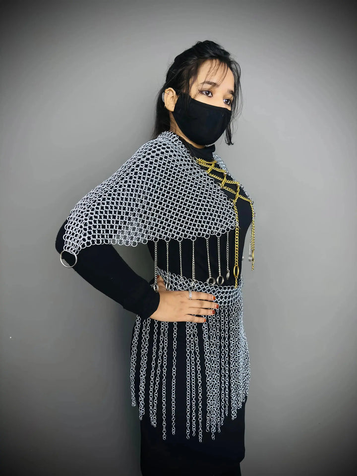 Person wearing a chainmail shirt with fringes on a gray background