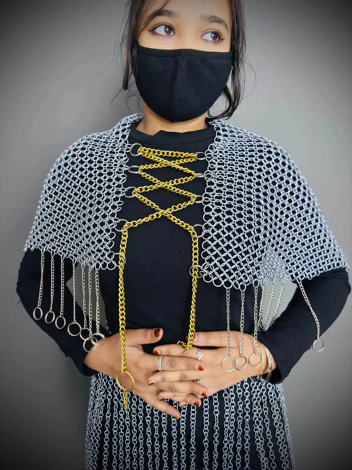 Person wearing a chainmail shawl with gold accents on a gray background